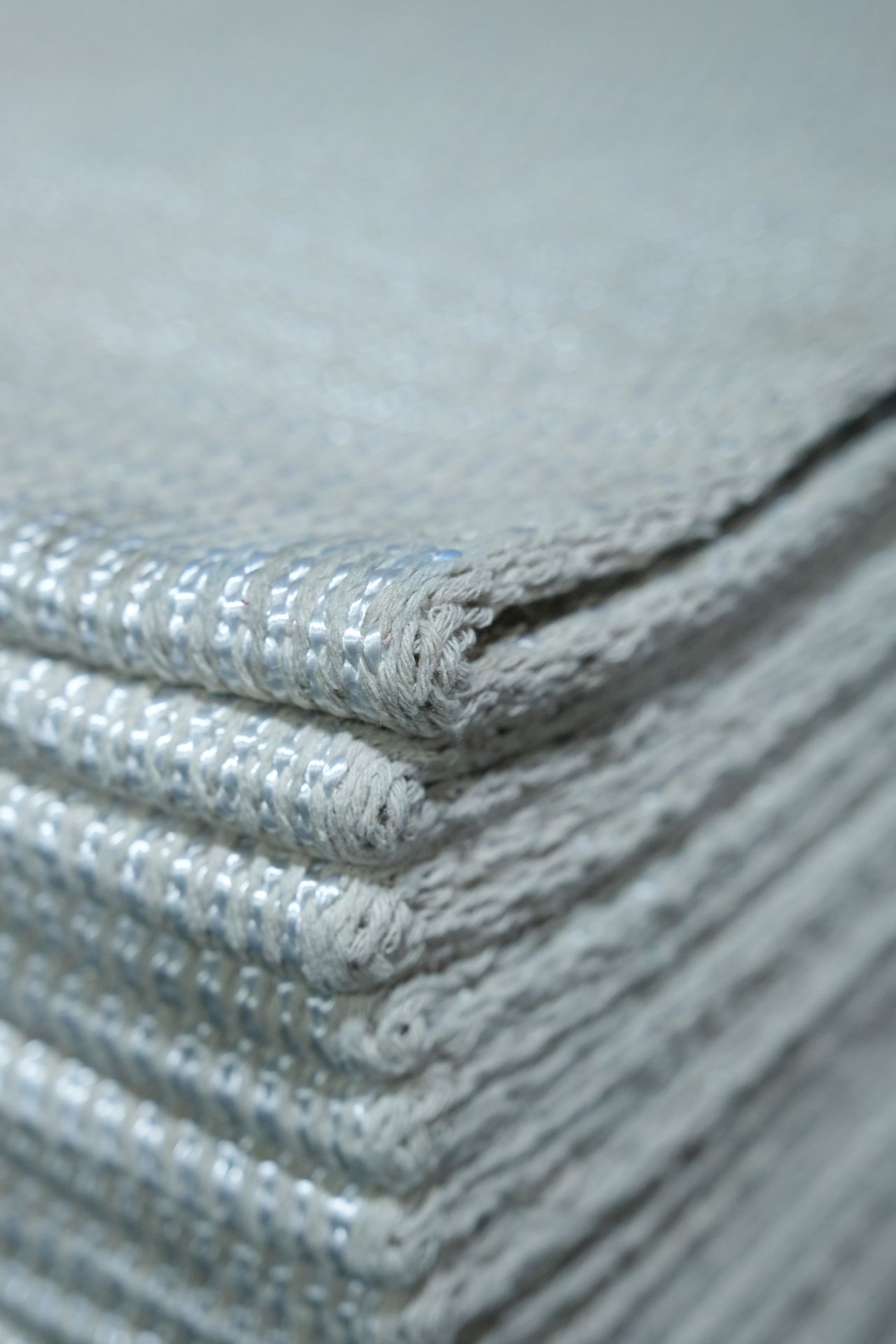 Smiling young woman with curly hair sitting at a laptop, in front of a teal wall.