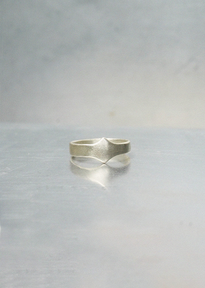 Silver ring on a reflective gray surface with a neutral background