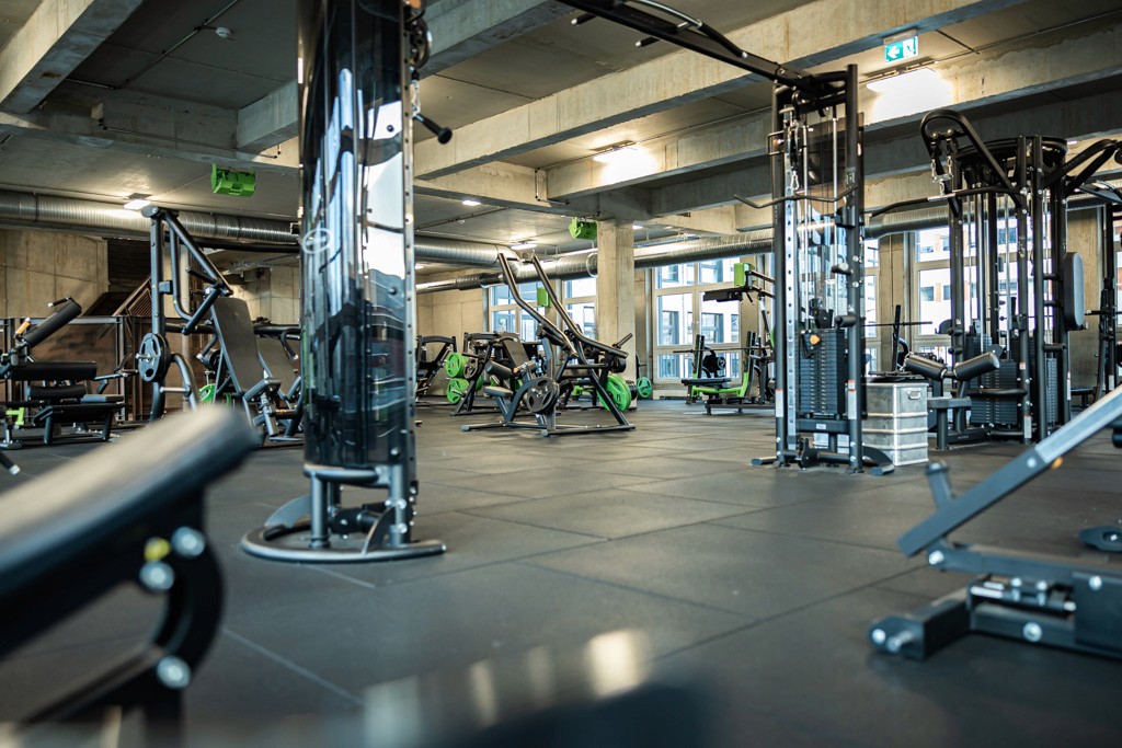 Freihantel-Bereich im XTRAFIT Fitnessstudio in Köln-Marsdorf mit modernen Kabeltürmen und großen Fenstern.