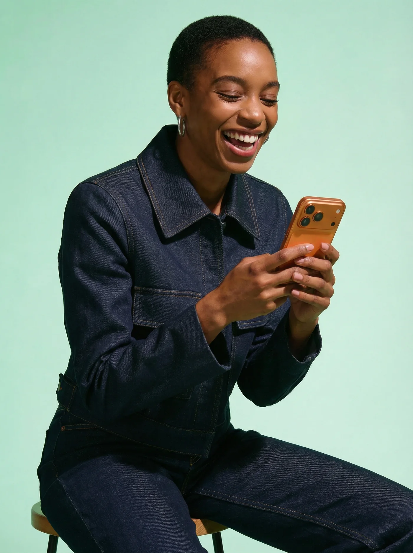 A woman laughing as she reads a message on her phone