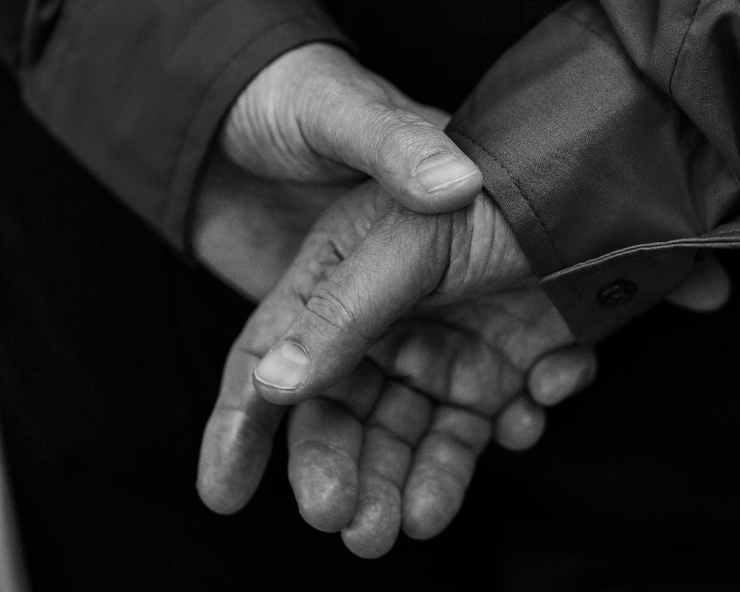hands of a worker in gloves holding a smartphone showing a green 'Verified' checkmark next to a digital ID card, industrial plant equipment in the soft-focus background
