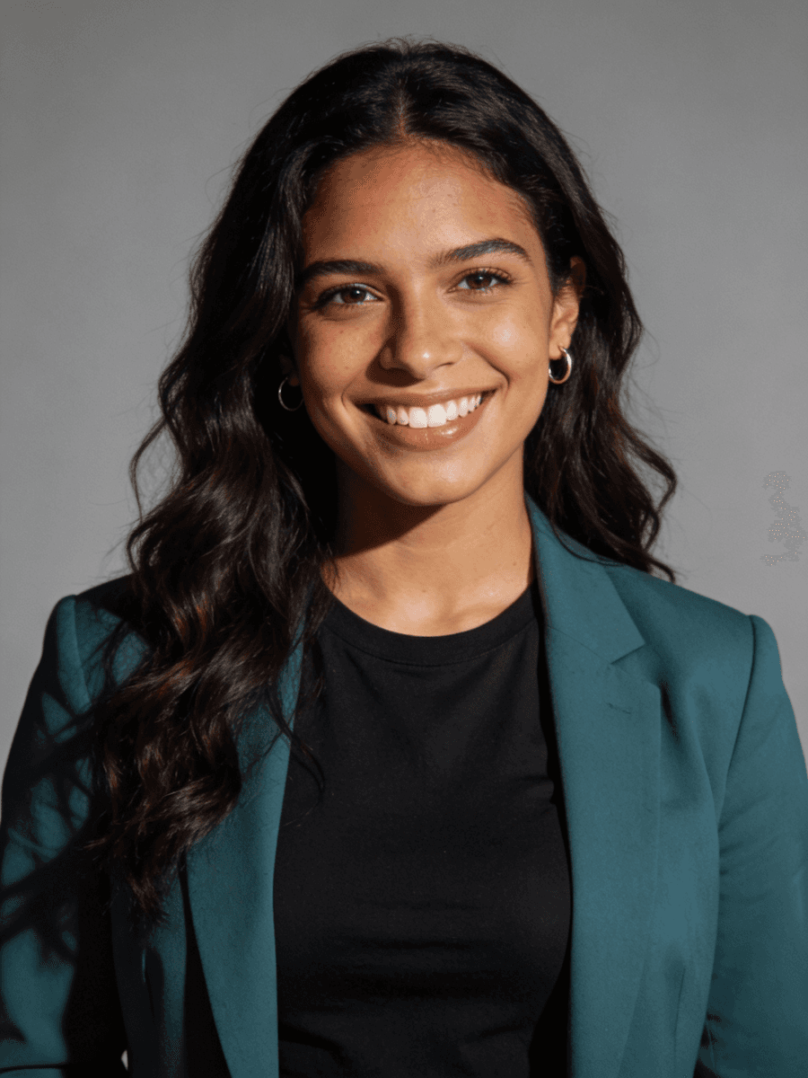 A woman dressed in a green blazer and black shirt, showcasing a professional appearance.