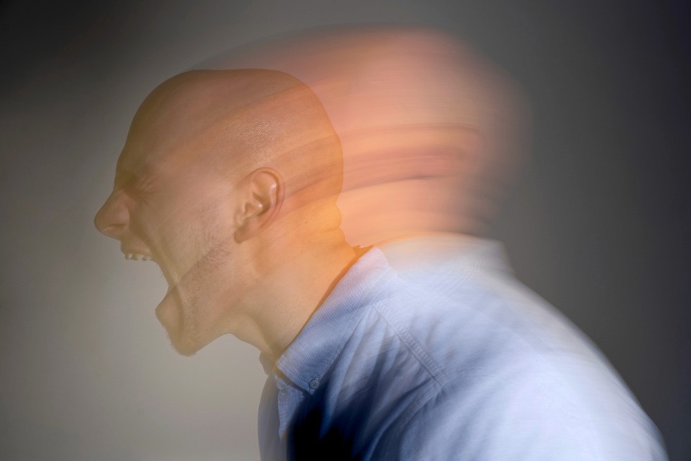 A man yelling with his face blurred in motion, representing trauma and emotional distress.