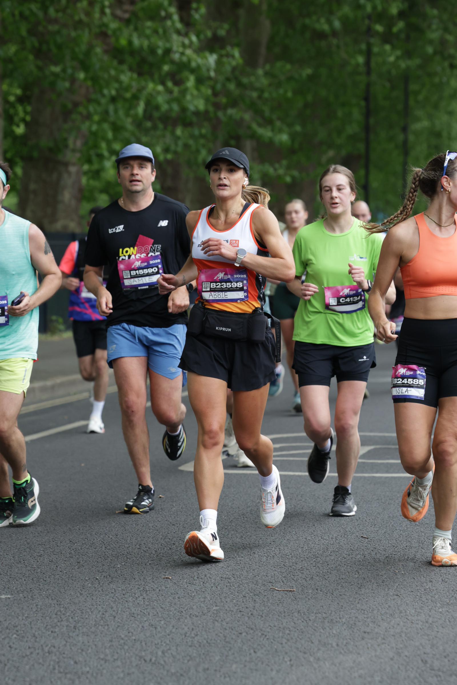 A winding road cuts through rocky terrain, surrounded by patches of green grass and illuminated by sunlight.