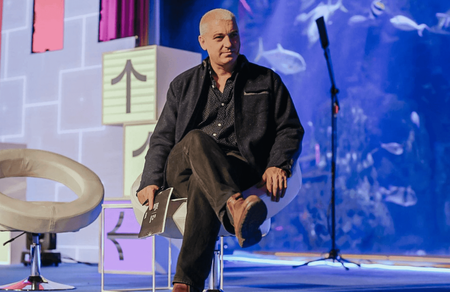 Person standing on stage singing and playing music.