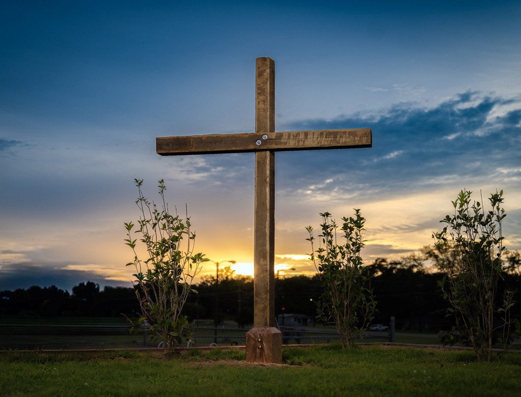 A chapel in a field with mountains in the distance at night