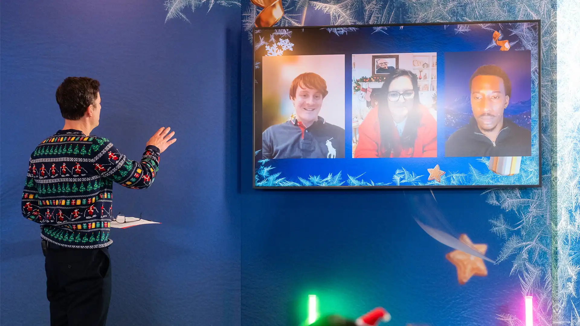 Presenter interacting with remote speakers displayed on a large screen during a live hybrid event.