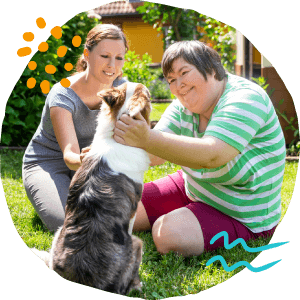 two people playing with therapy dog in a yard