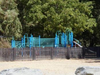 Play equipment behind a low fence at Tooby Memorial Park.