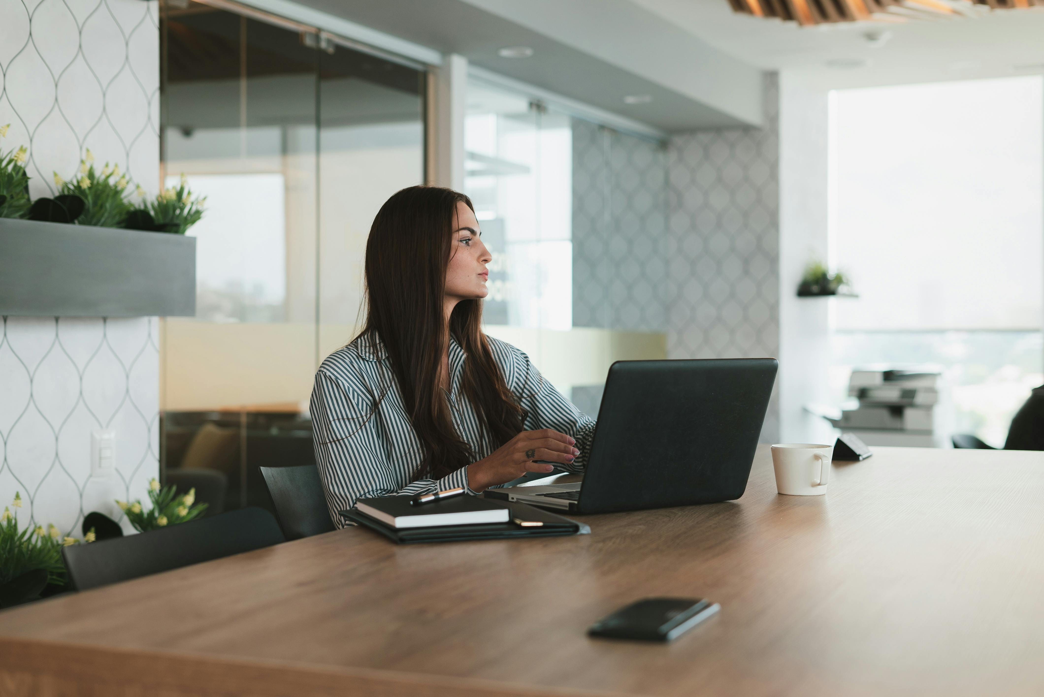 Donna che lavora al computer in una sala riunioni, momento di riflessione sul proprio ruolo professionale e sul significato del lavoro all’interno dell’azienda