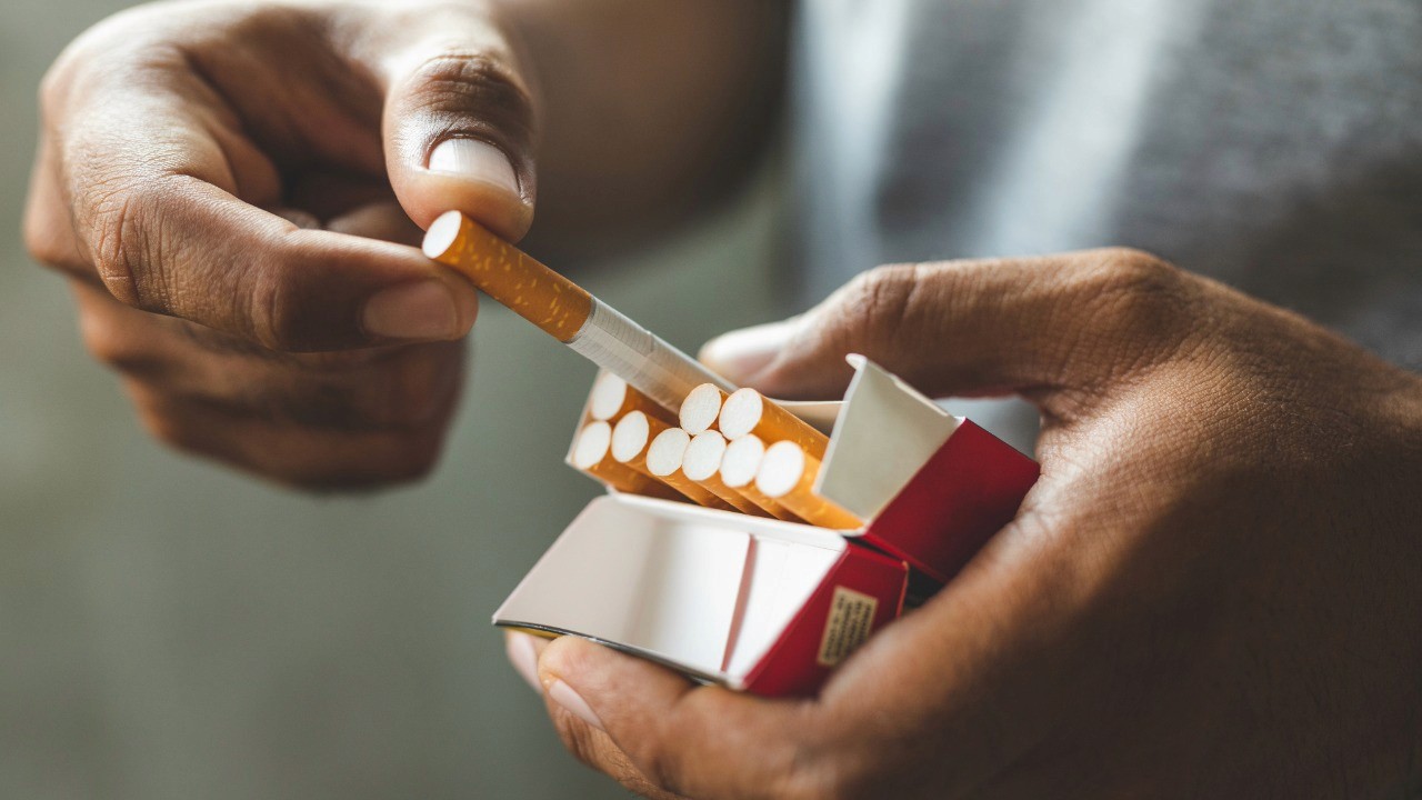 close up of hands taking a cigarette out of a box