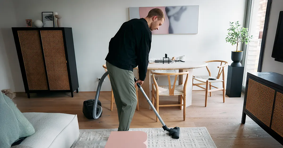 Illustrasjonsbilde av en mann som støvsuger i stuen.