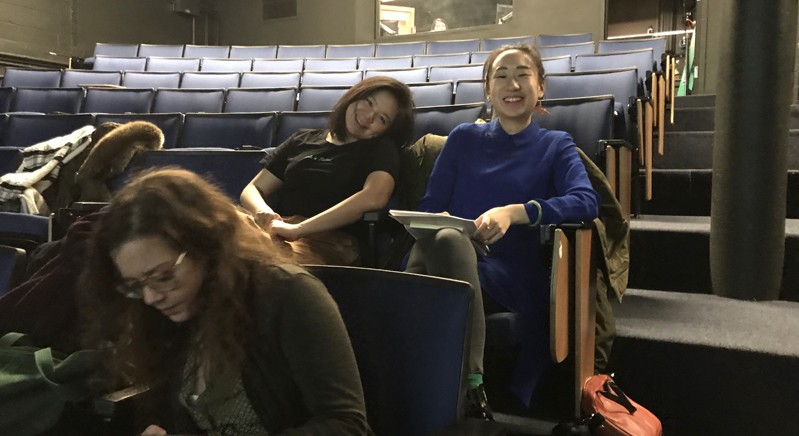 A photo of a group of people sitting in a theater room.