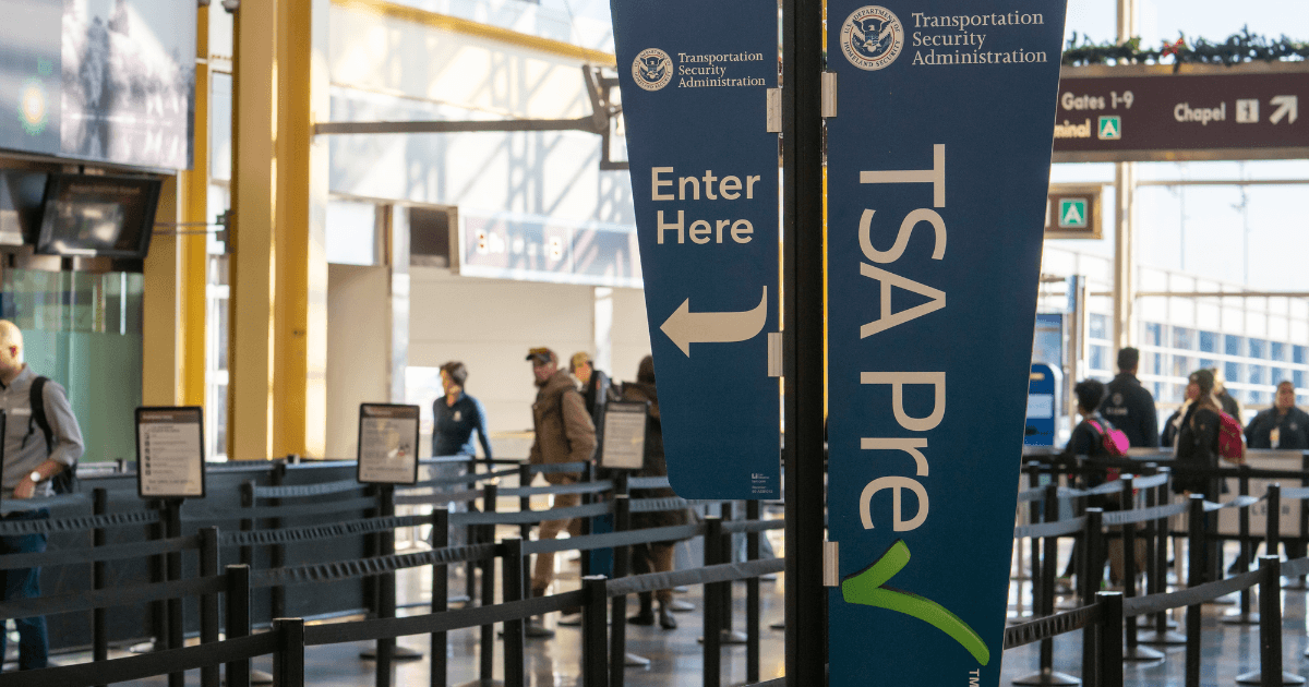 Travelers moving through a TSA security checkpoint with carry-on luggage