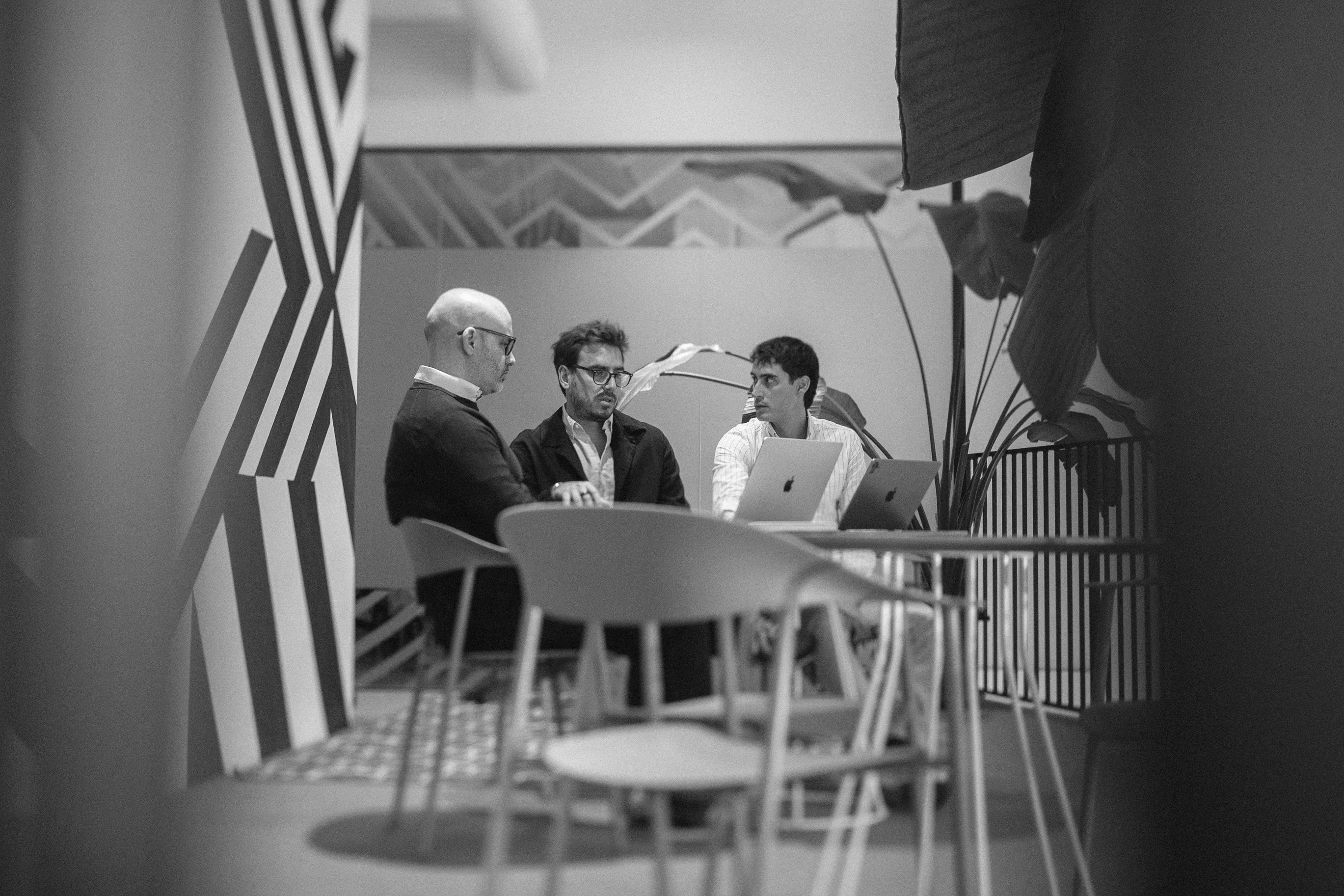 Tres personas revisando planos en una oficina luminosa.