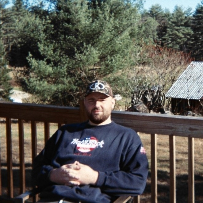 Portrait of man looking to the left and smiling with a dark background