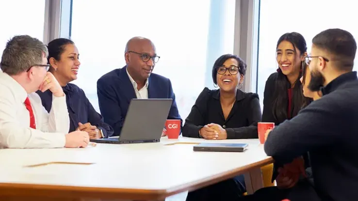 Diverse team members collaborating around a meeting table in a modern office.