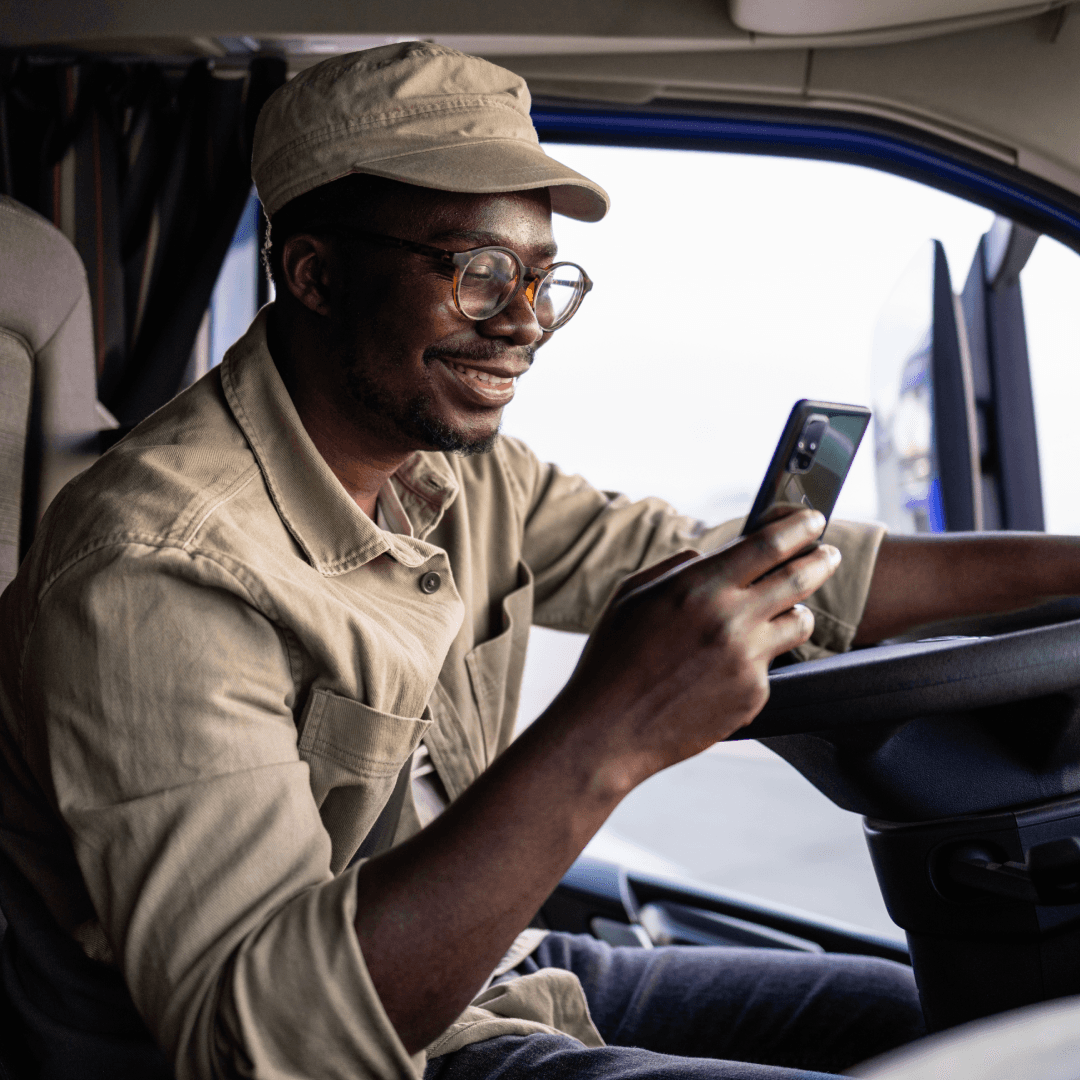 Truck driver completing digital check-in on mobile device inside cab before warehouse dock assignment
