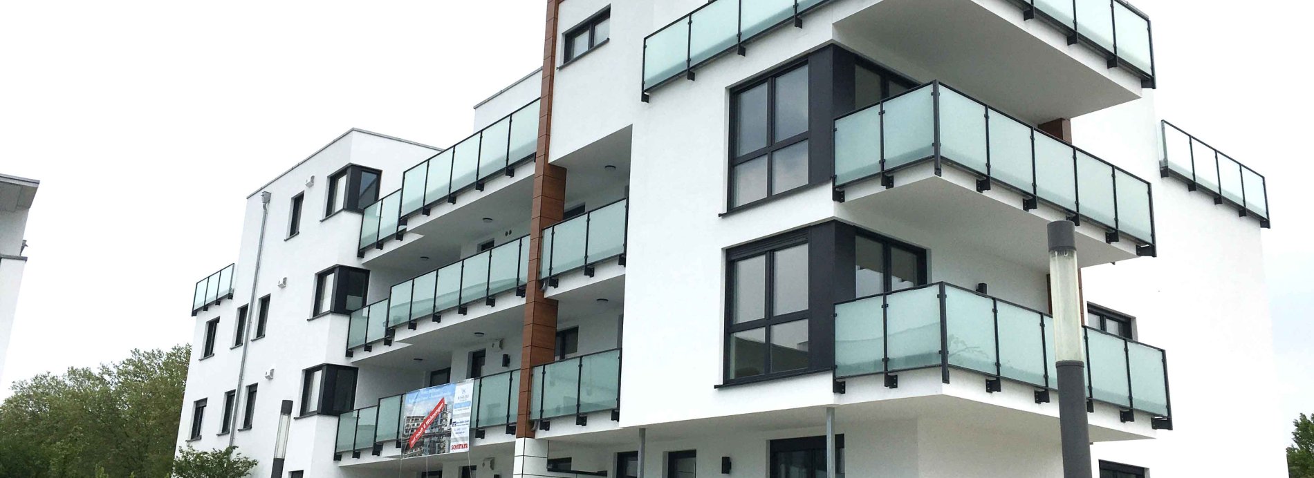 Modernes Wohngebäude mit Balkonen und Glasgeländern. Architektur, Immobilien und Wohnen.  Weißes Haus.