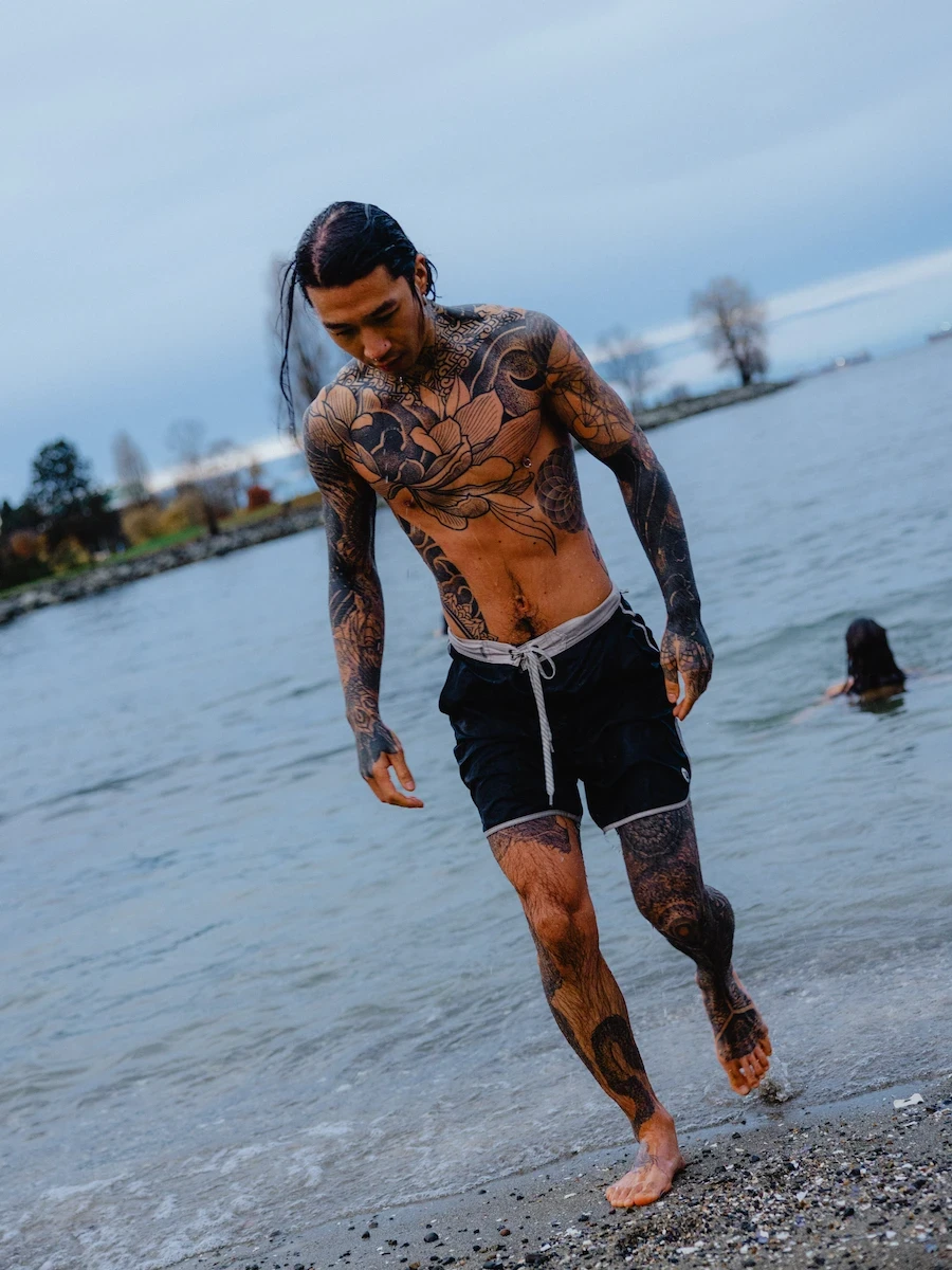 Man stepping out of cold water after heat exposure, showcasing the benefits of sauna and cold plunge.