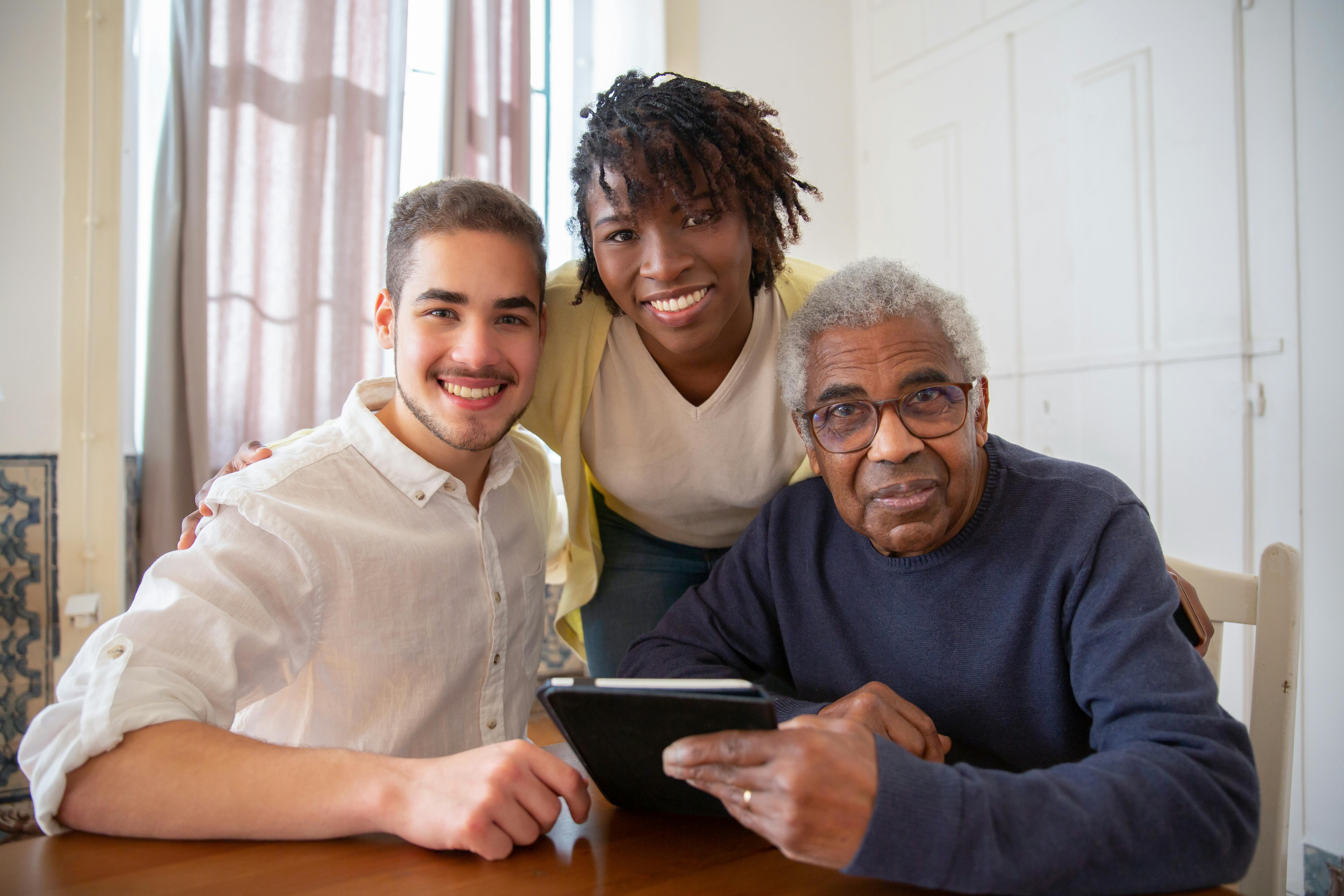 Two adults helping a third older adults with their tablet.
