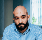 man in blue and white checkered dress shirt and black denim jeans sitting on concrete bench