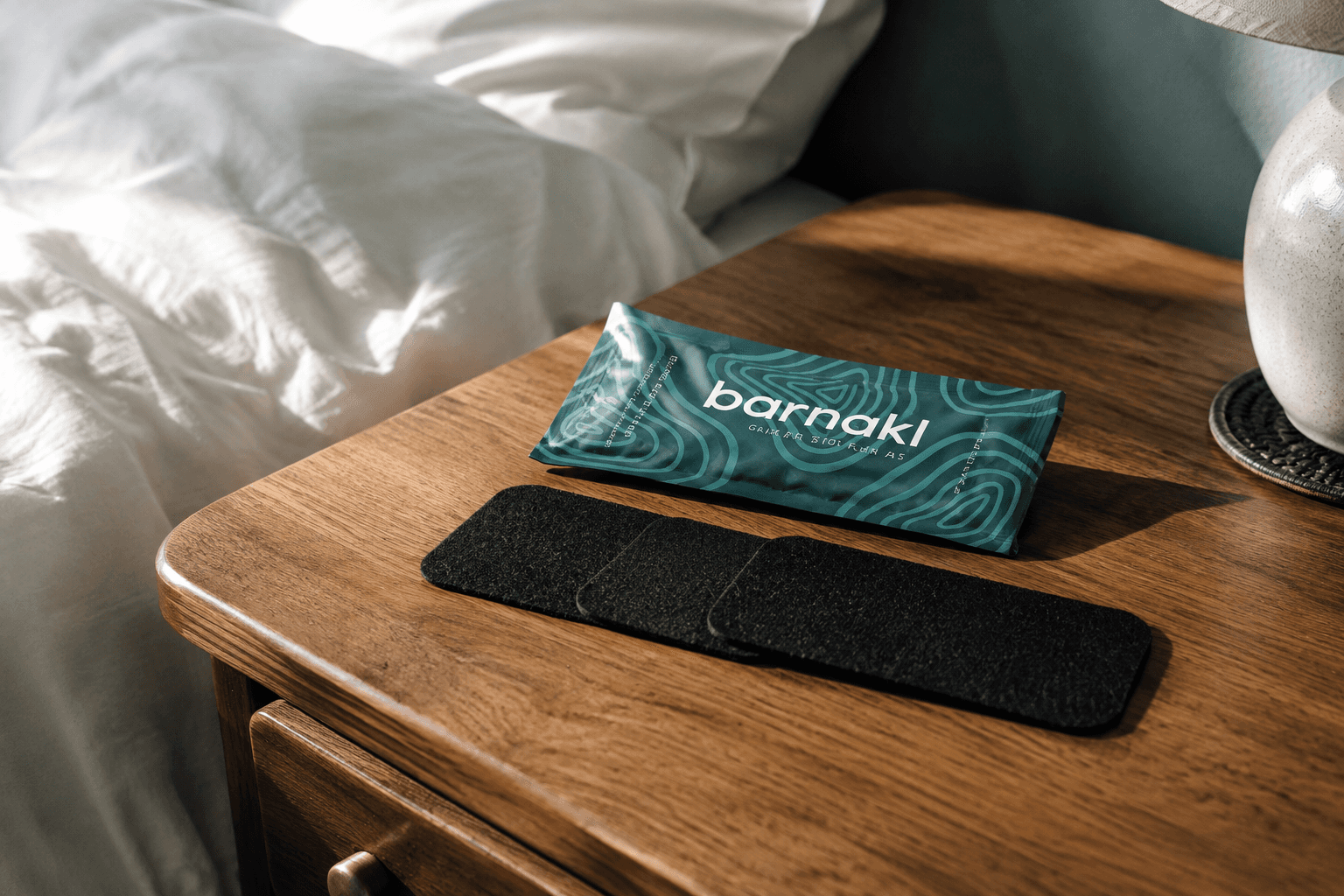 Barnakl's teal pack and three black filters on a bedside table in morning light