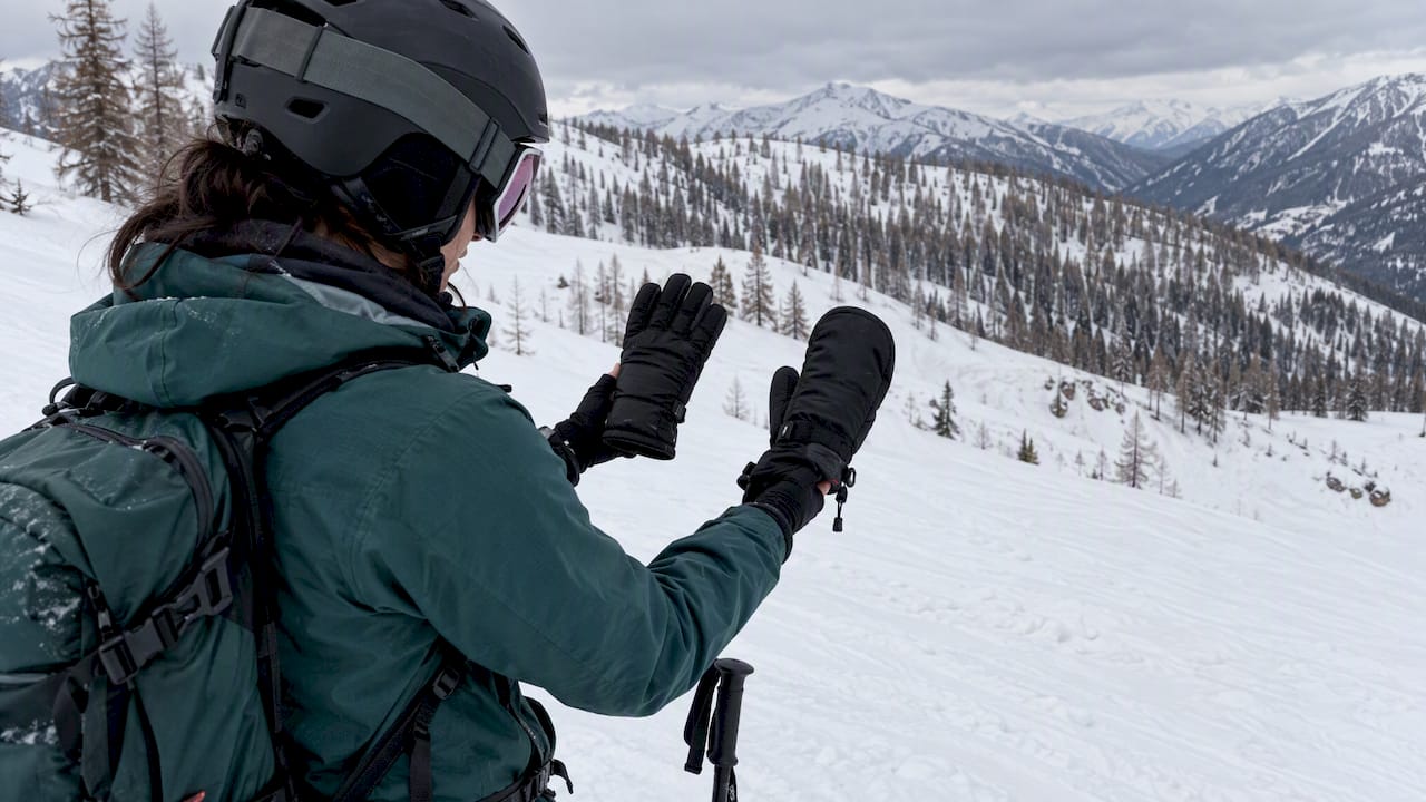 Skier holding an insulated ski glove and mitten for comparison