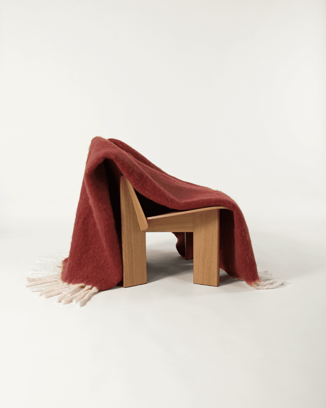 Faux mohair blanket in pomegranate/moon draped on wooden chair