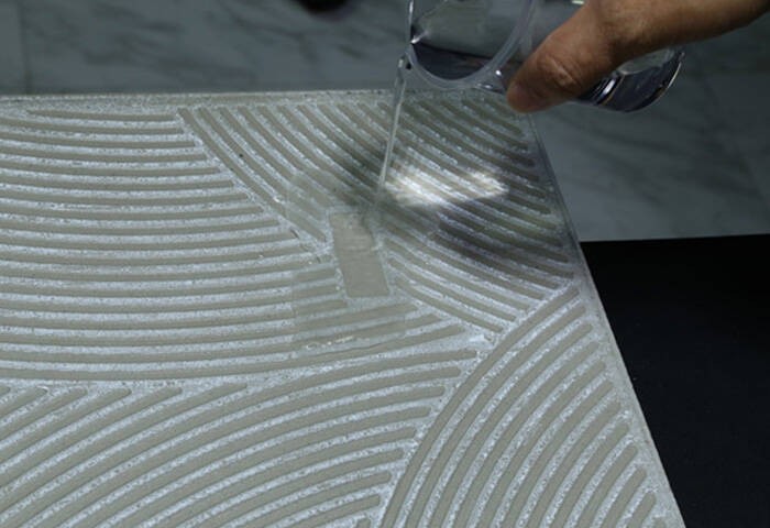 Water being poured onto a grooved stone surface, highlighting the stone’s drainage and water resistance features.