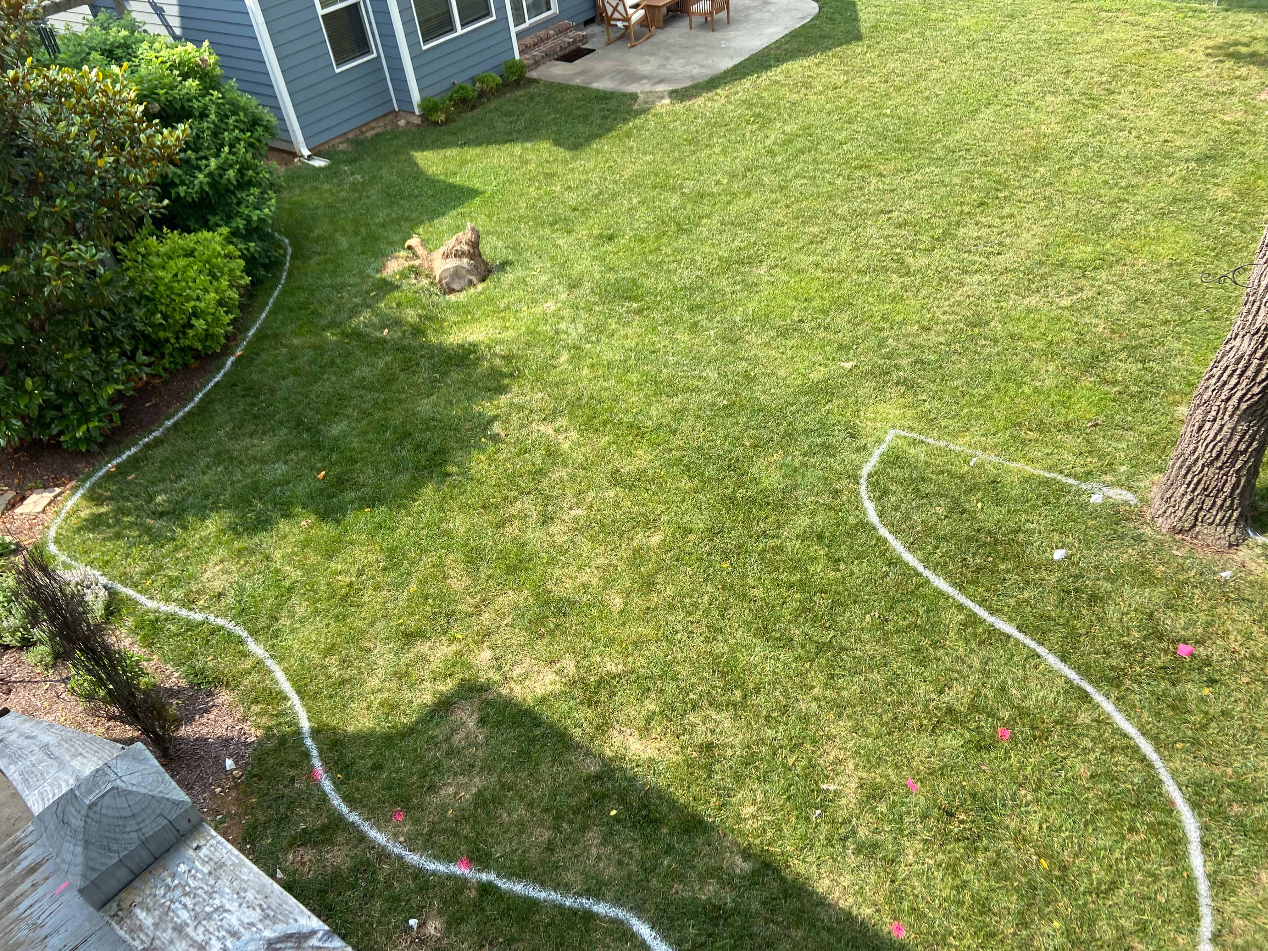 Backyard lawn with white painted landscape bed layout.