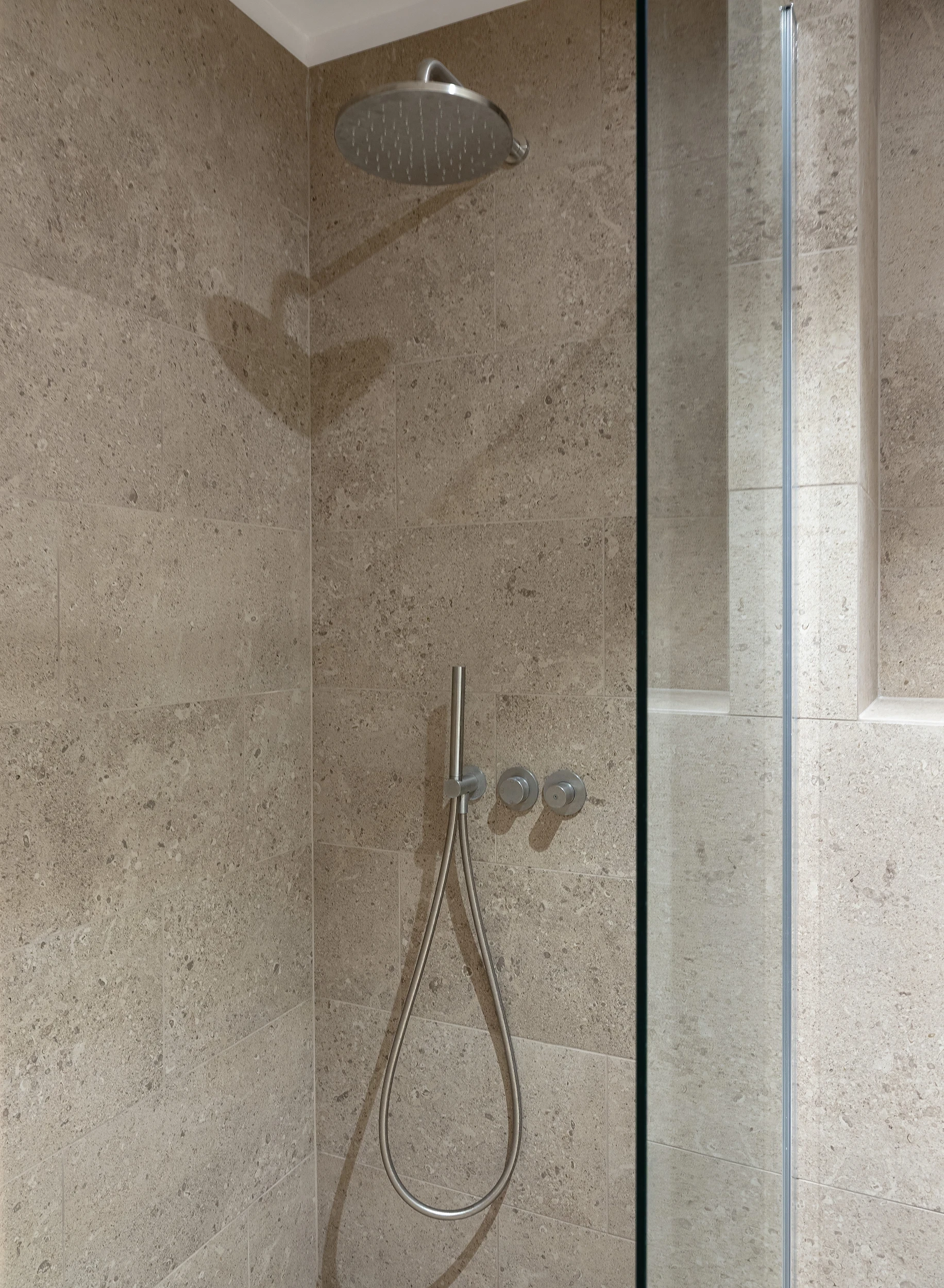 Solution de douche optimisée avec robinetterie encastrée et paroi de douche sur-mesure en bois sombre.