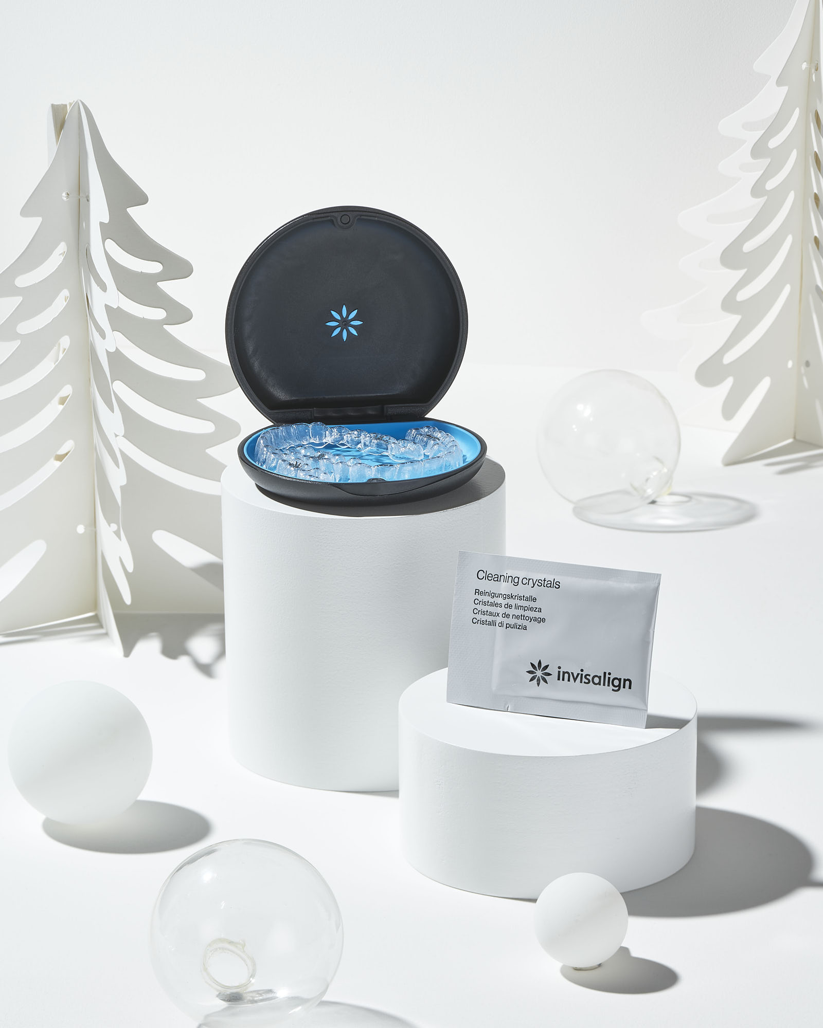 Invisalign clear aligners in case with cleaning crystals, winter-themed background.