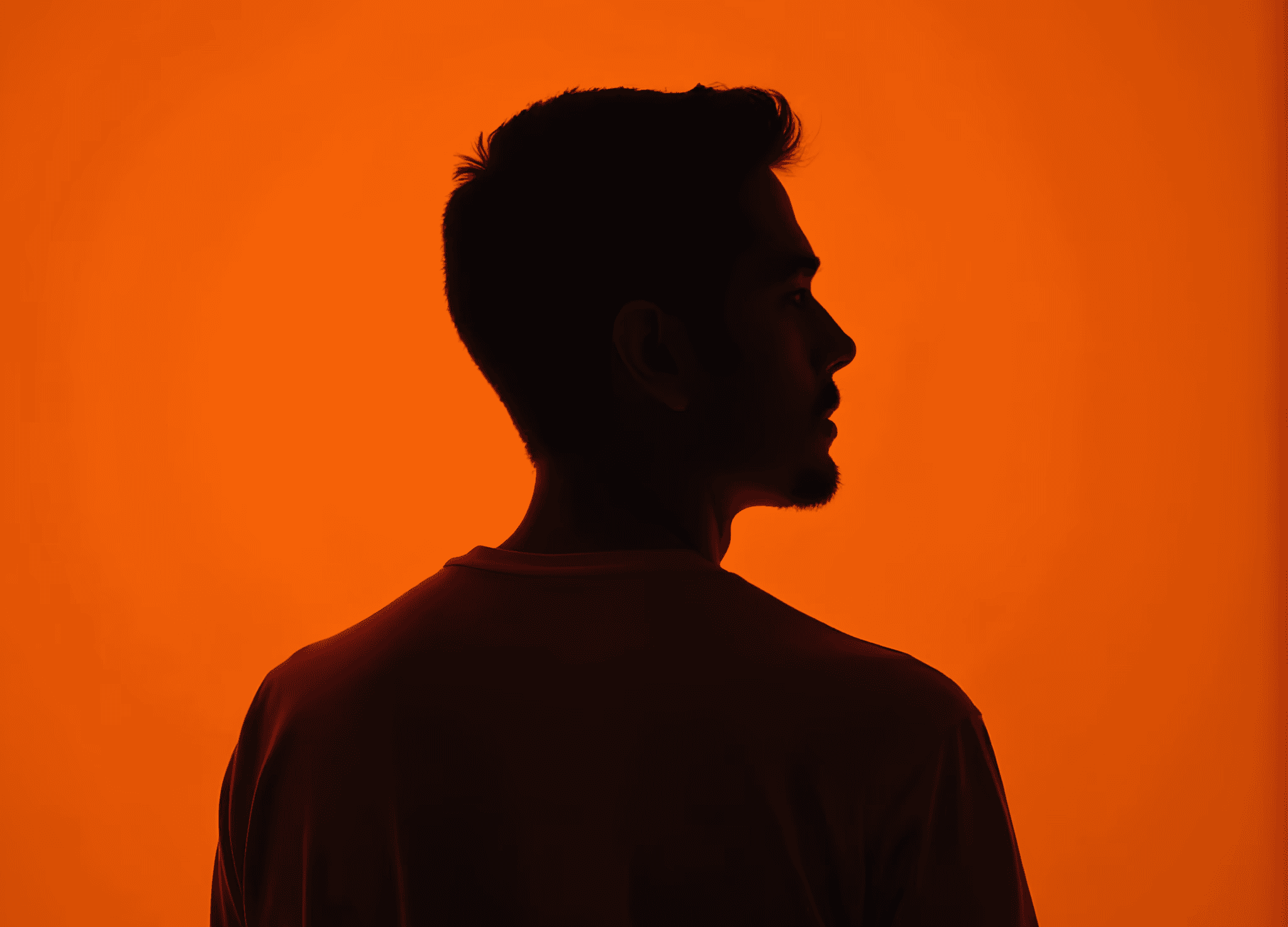 A silhouette of a man stands against a vibrant orange background, creating a striking visual contrast. Created with AI midjourney