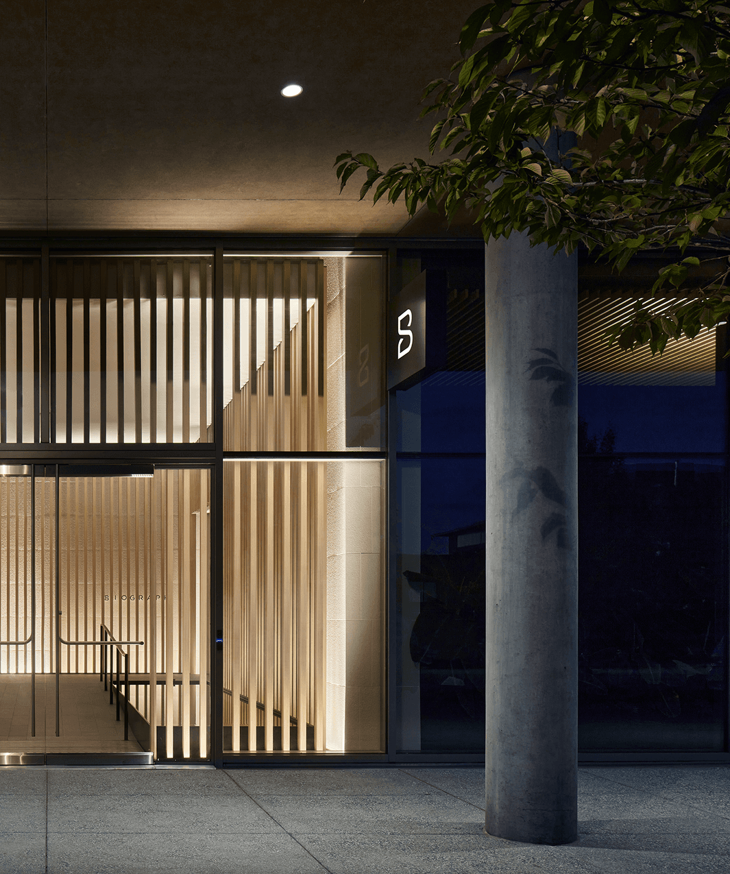 Exterior view of the Biograph clinic in the San Francisco Bay Area, featuring a modern facade with vertical wood slats, soft interior lighting, and minimalist architectural details at dusk.
