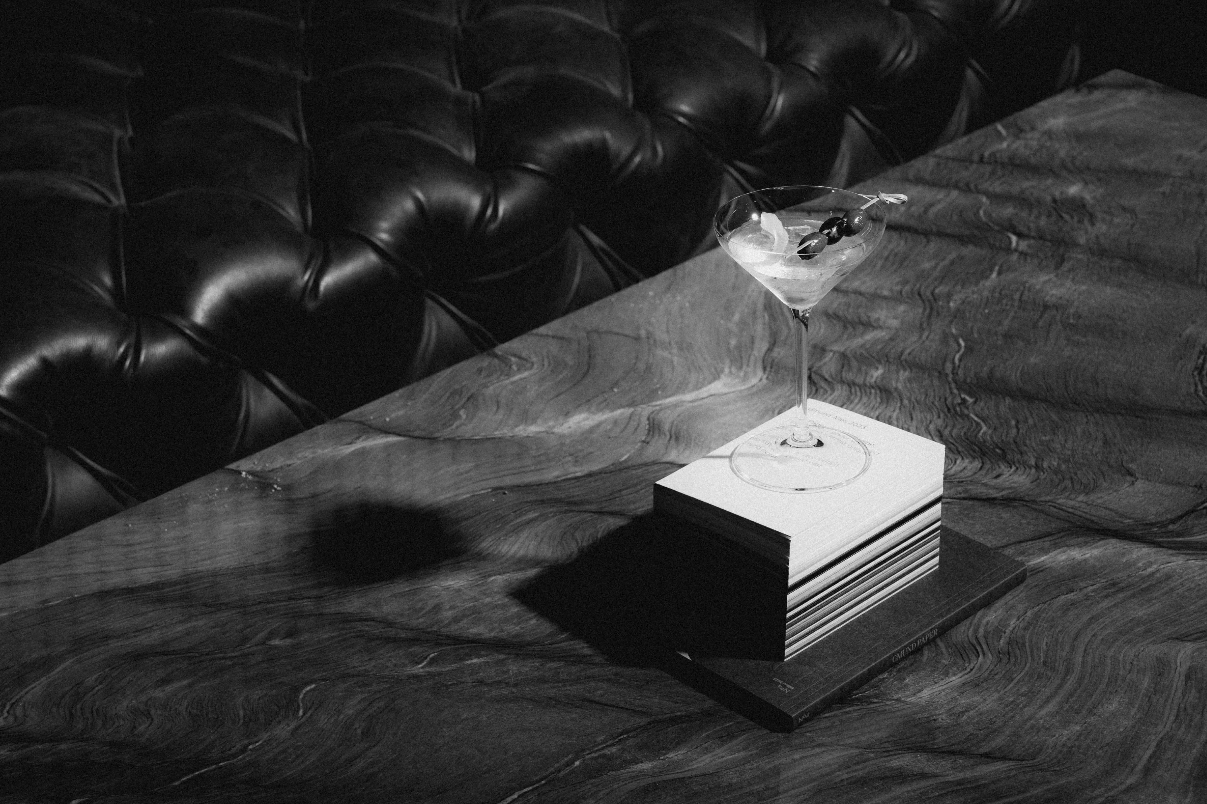 A small white box rests on a dark surface, partially illuminated, with shadows in the background.