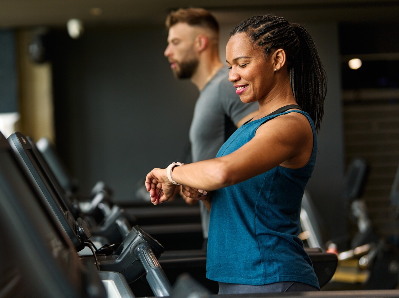 woman checking her smart watch at the gym to see how long she’s been walking on treadmill for weight loss