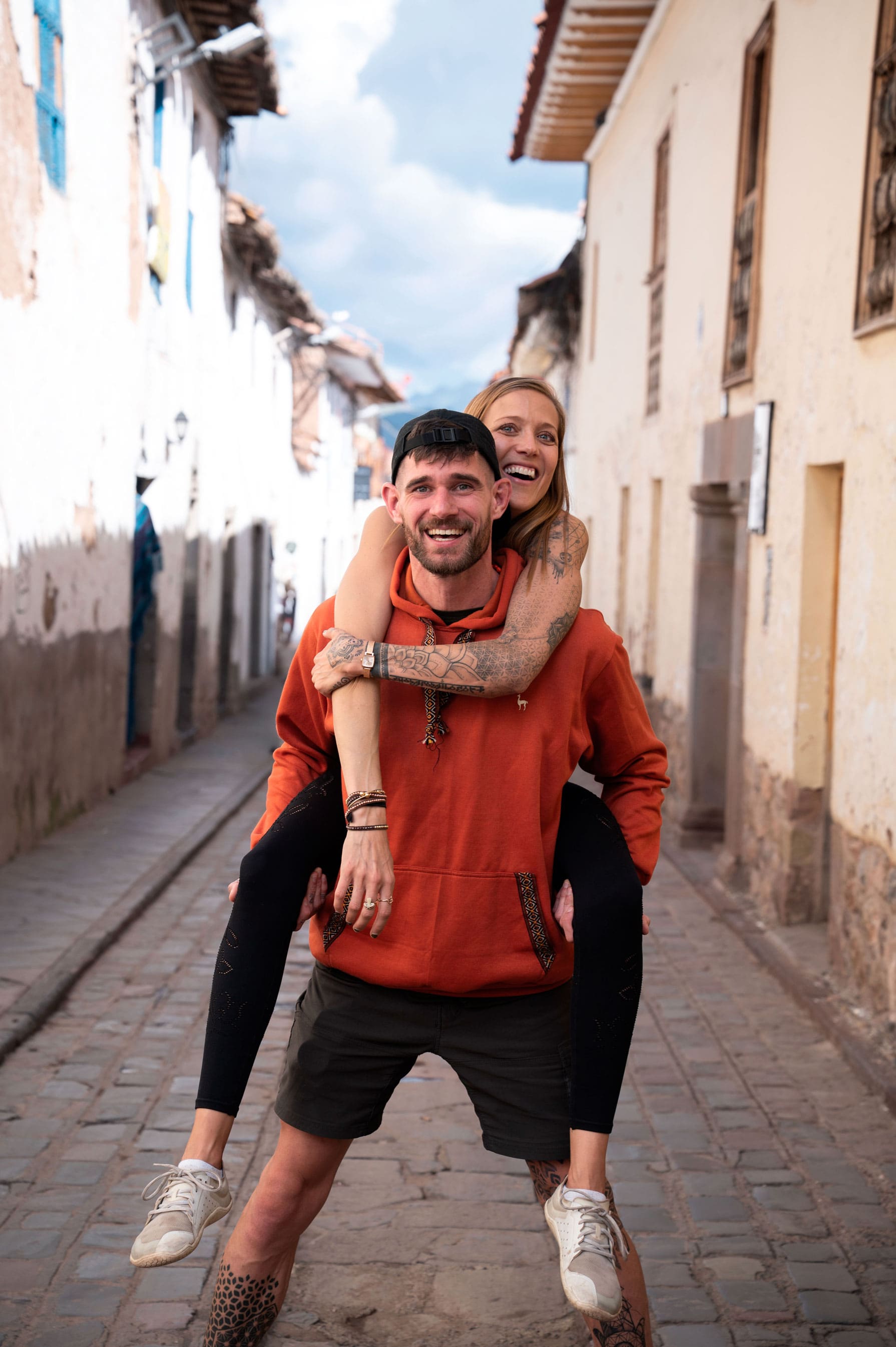 Bre and Flo smiling in a sunlit street.