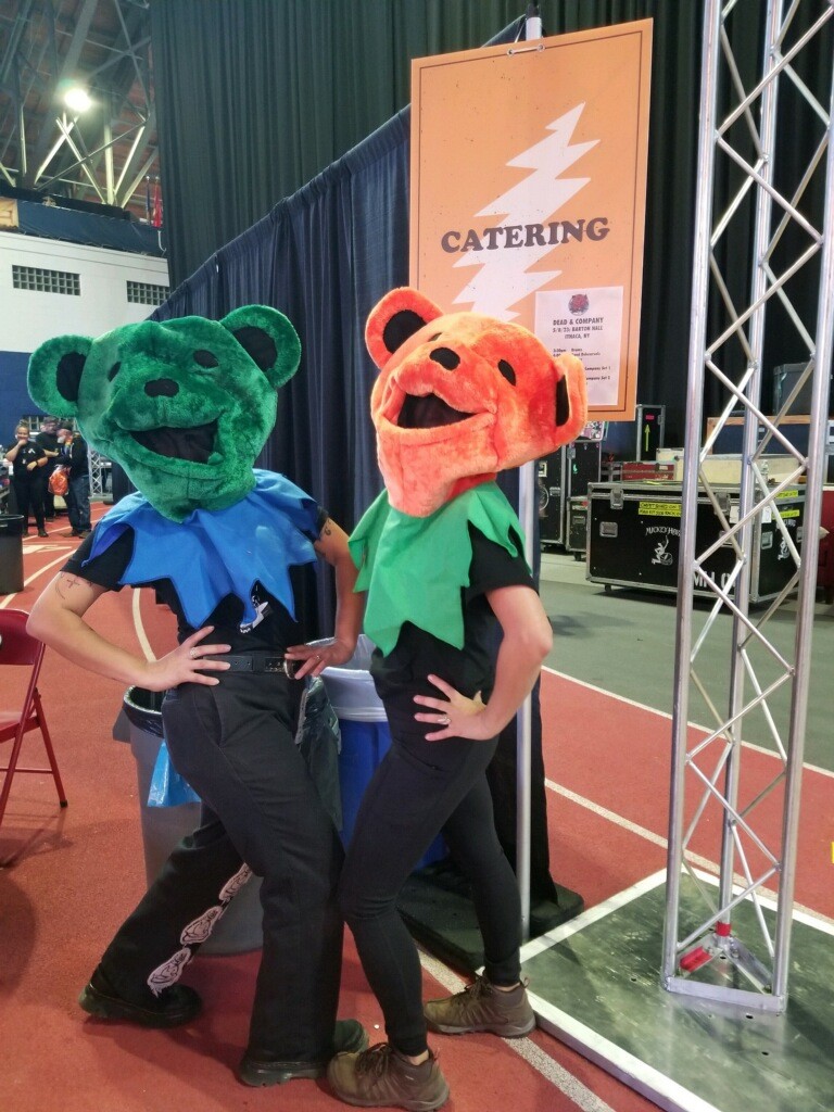 Two individuals in colorful animal mascot costumes stand together at an event, smiling for the camera.