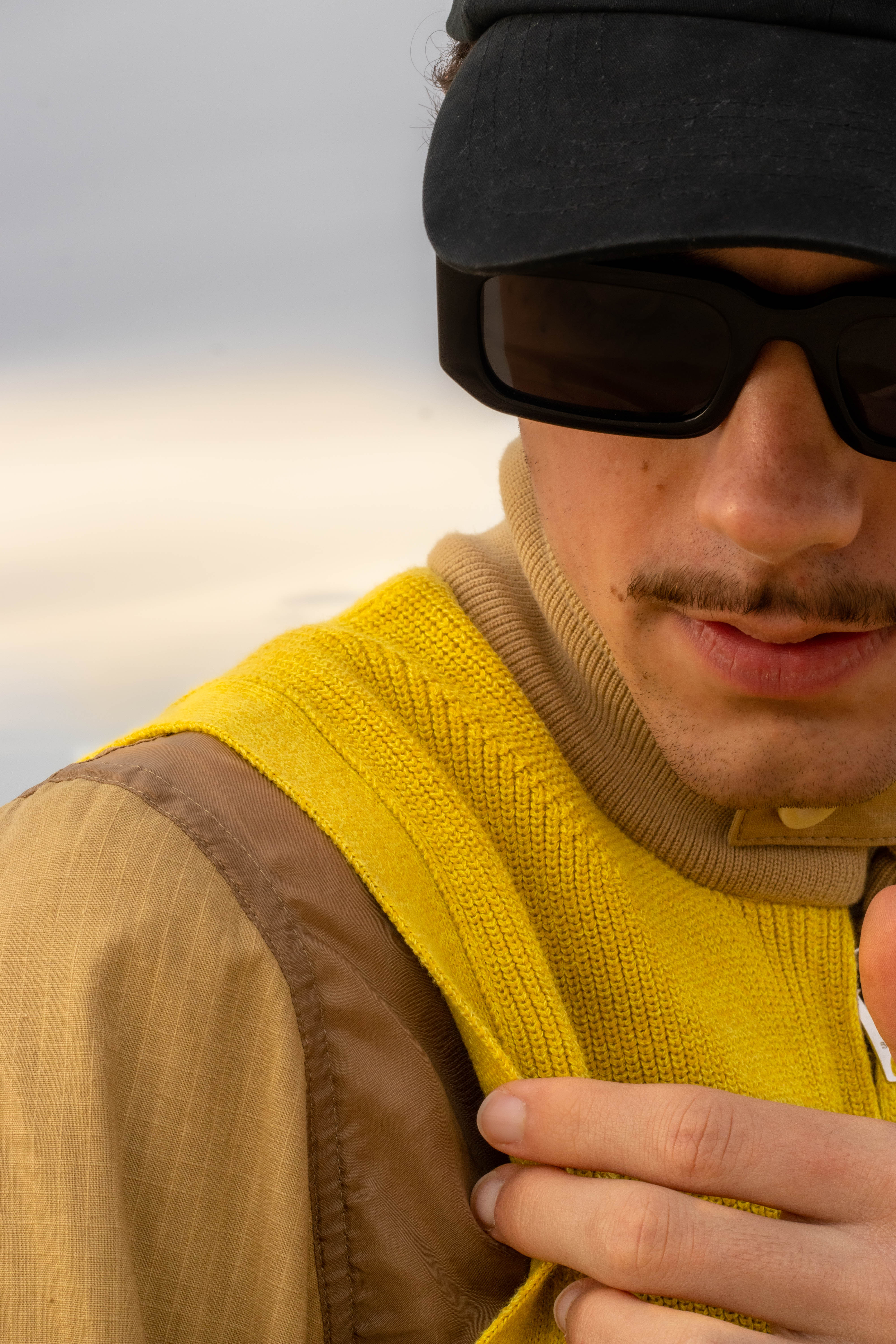 shooting masculin nature proche de l'océan, une tenue jaune très vif qui contraste avec le blue de l'eau