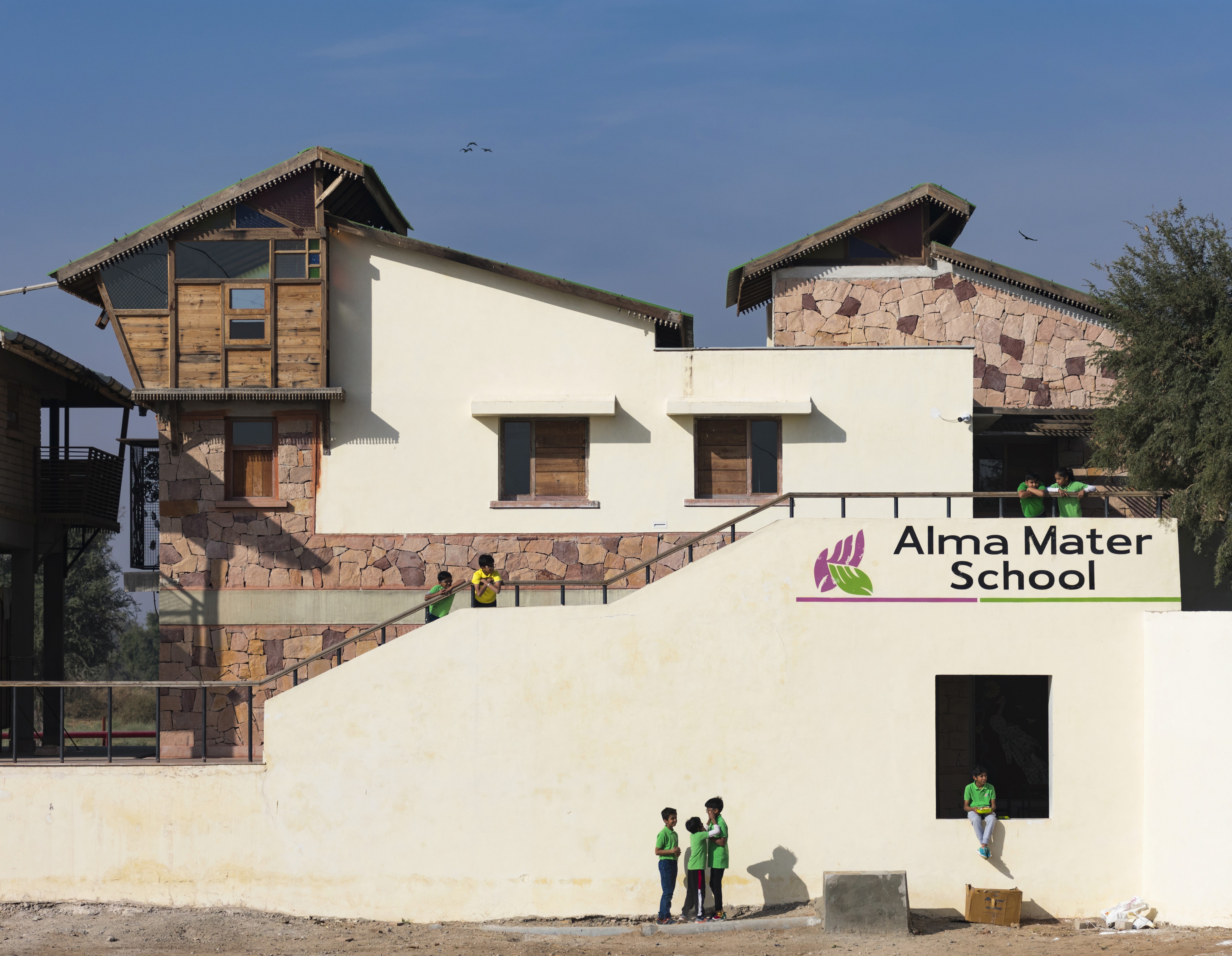 Two schoolgirls holding books are talking near a school building