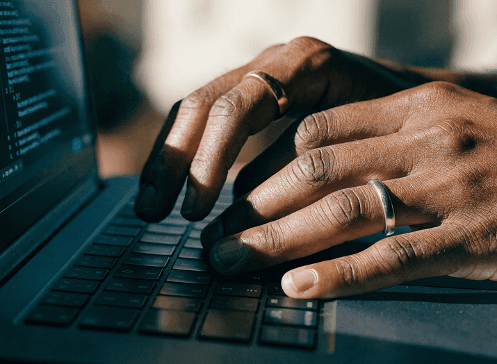 Mãos digitando em um teclado de notebook.