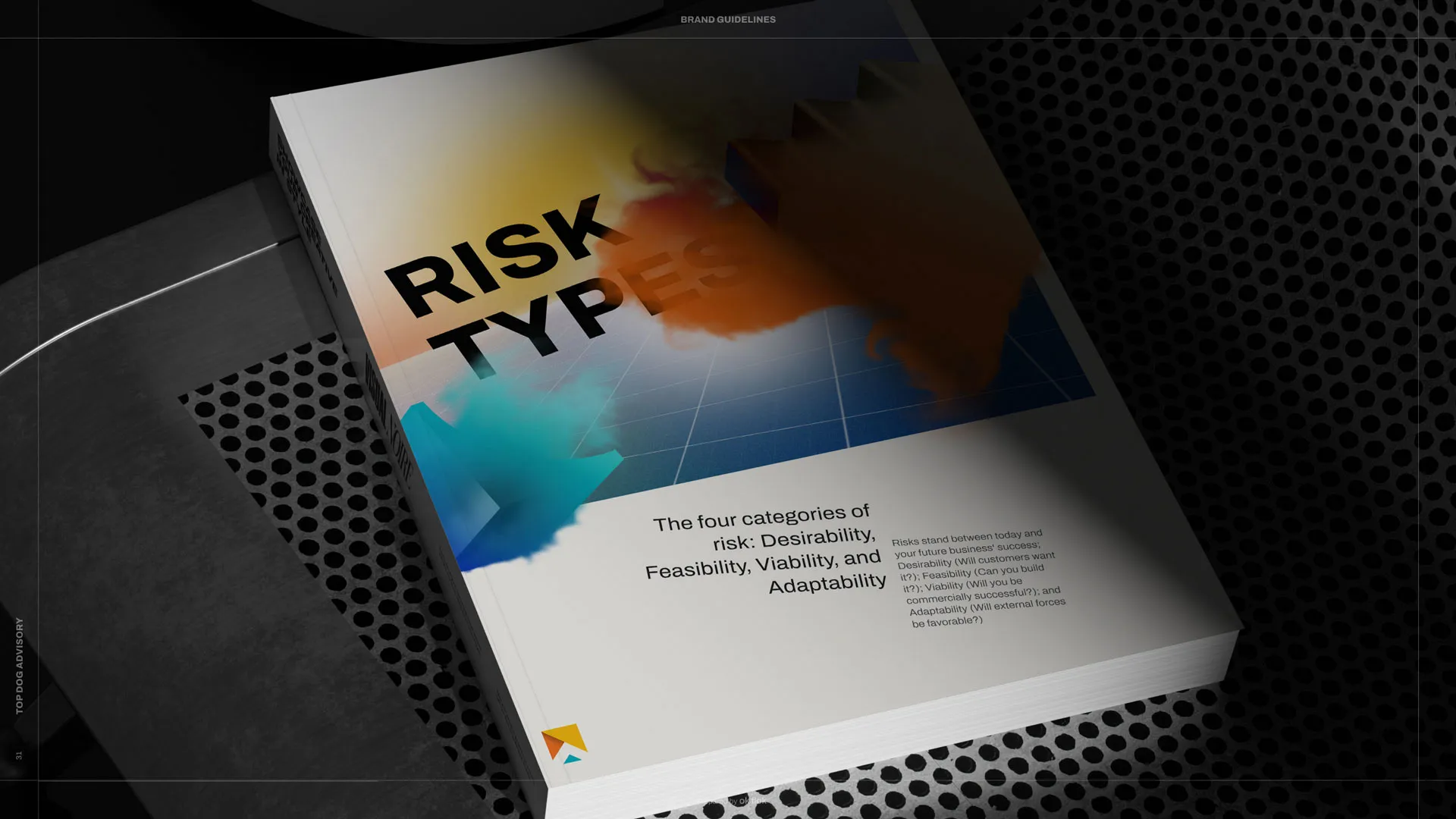 A book with a colorful cover lying on a dark surface, partially obscured by shadows.