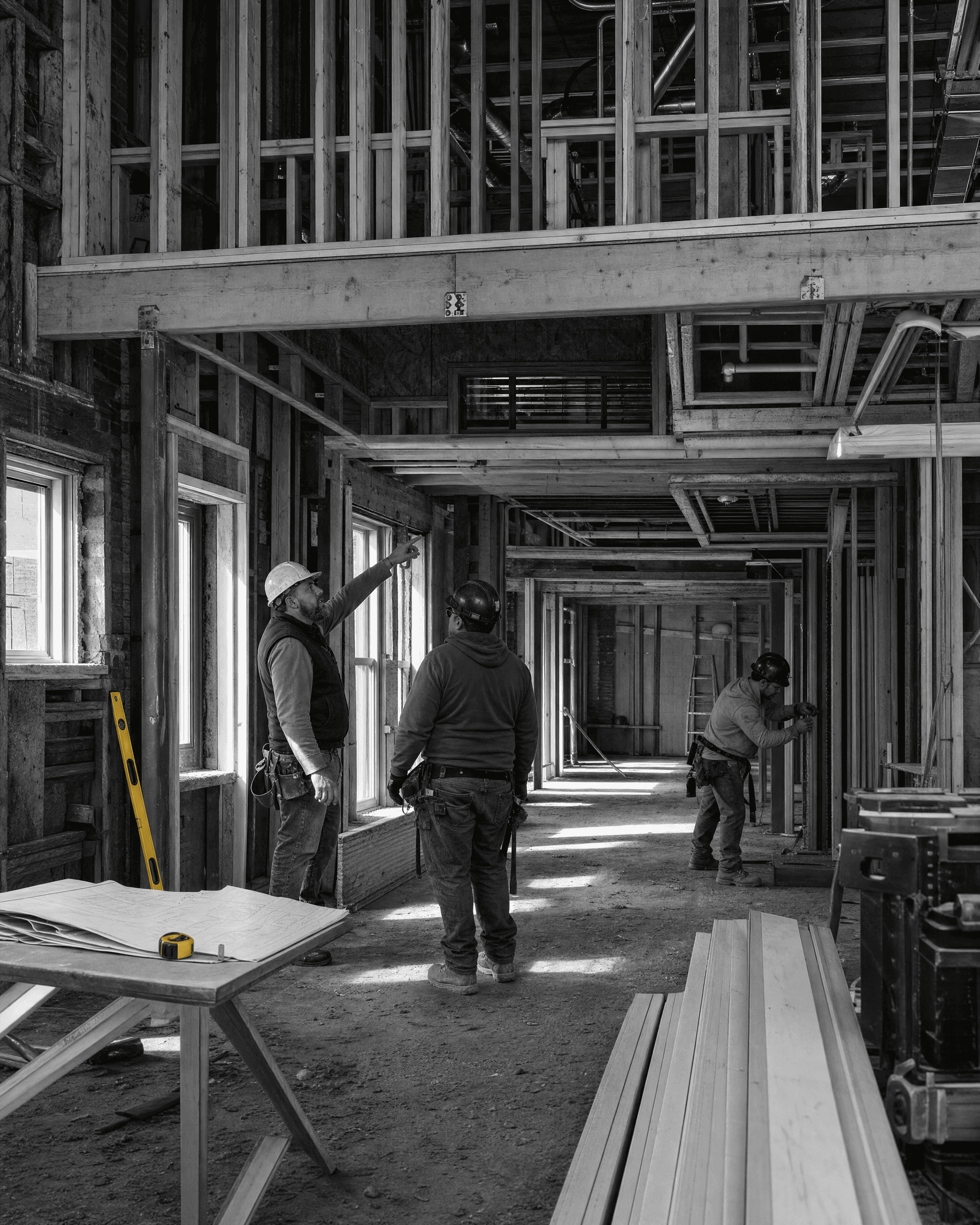 Construction lead pointing out framing conditions while trades coordinate work inside a large renovation.