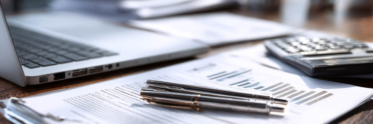 Picure of a calculator and pens and paperwork on desk