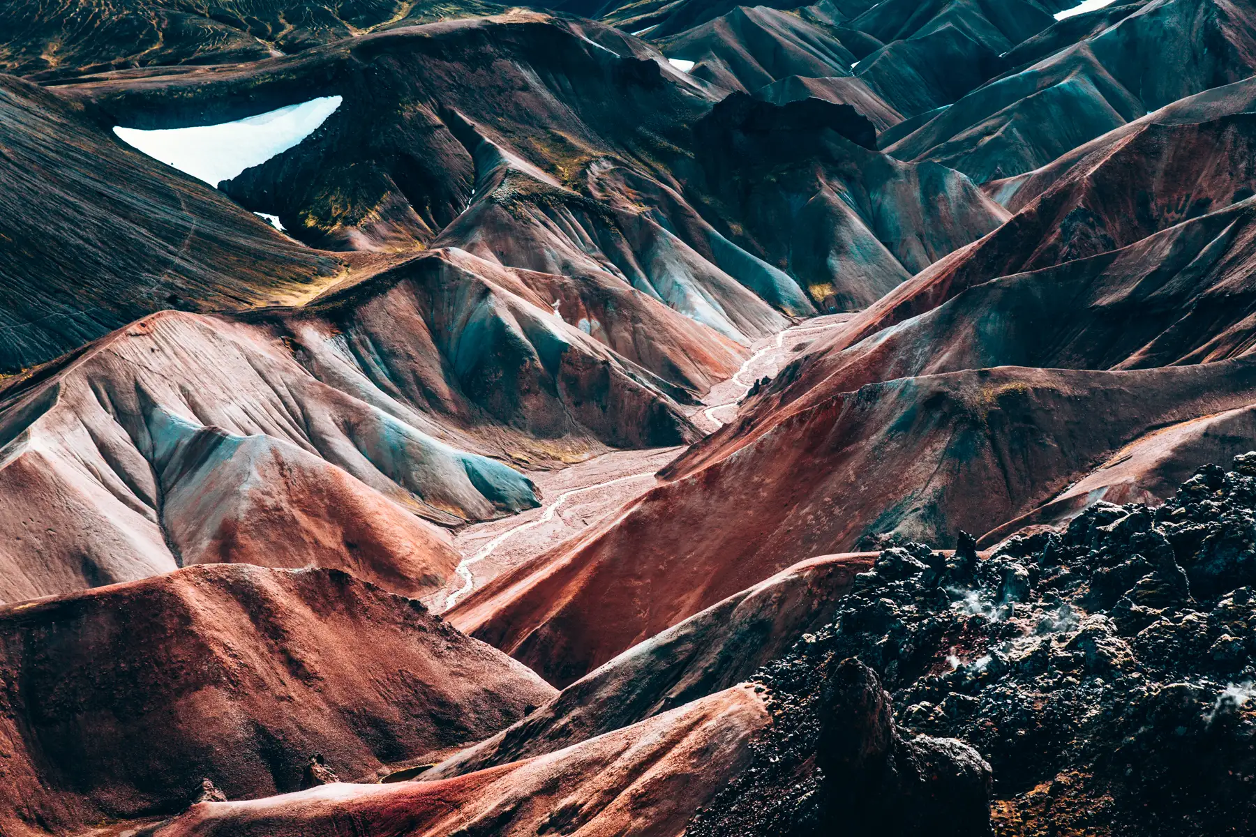 Aerial of rhyolite mountains banded in rust, cream and black
