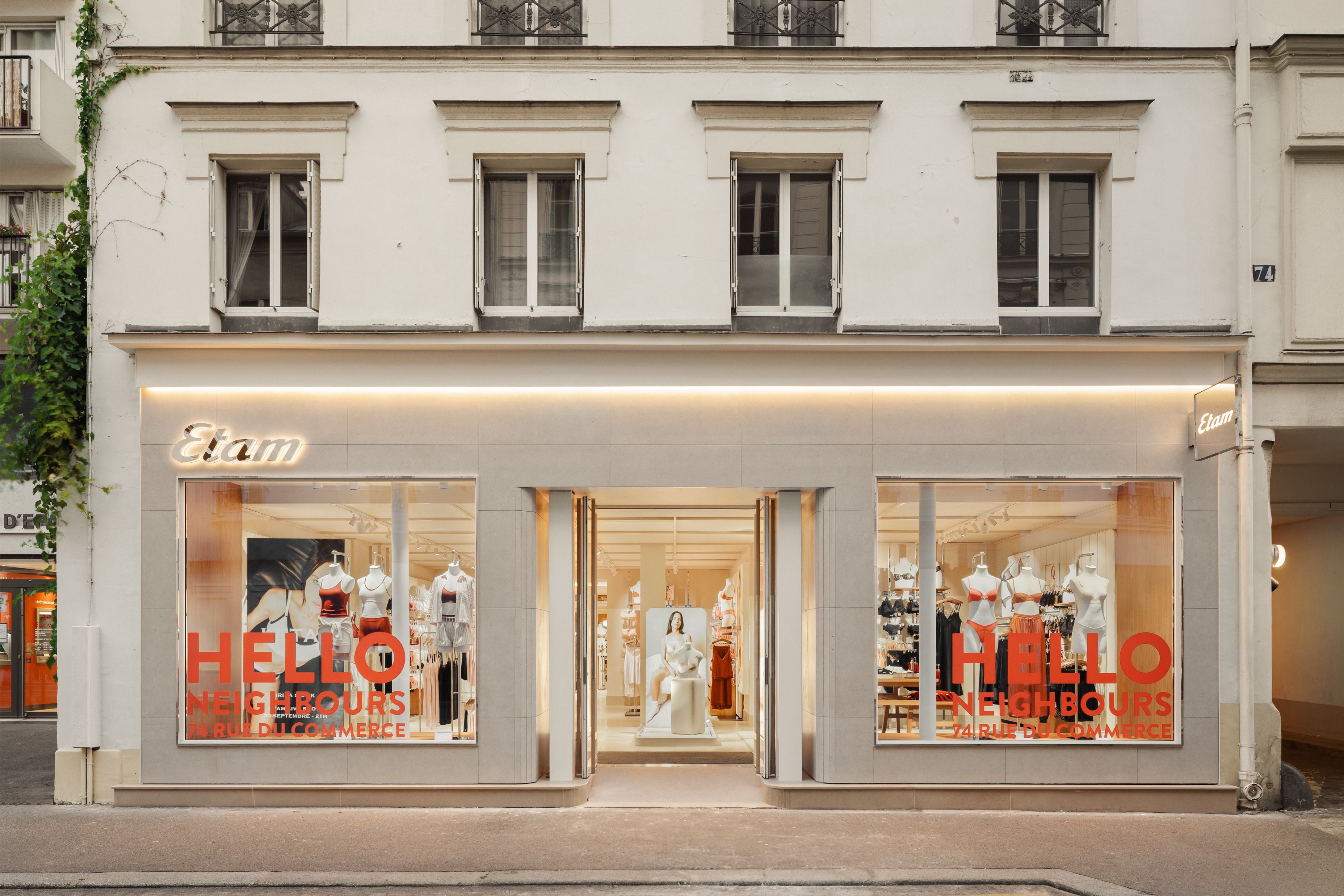 Façade de la boutique Etam au 74 rue du Commerce, avec l’inscription "HELLO NEIGHBOURS" en vitrine.
