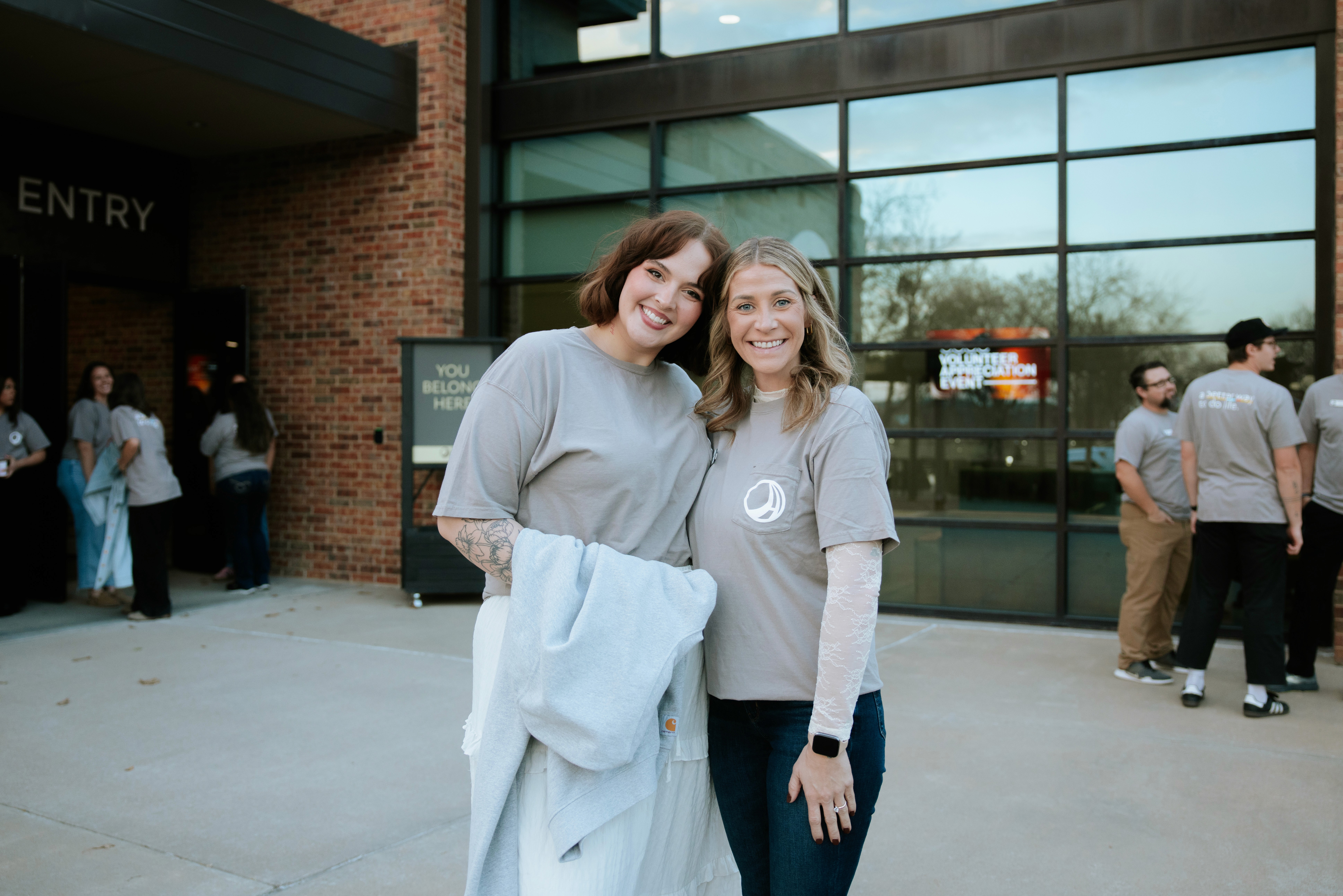 Two speakers present in front of an audience, with a large screen displaying "Mighty First Mentors" behind them.