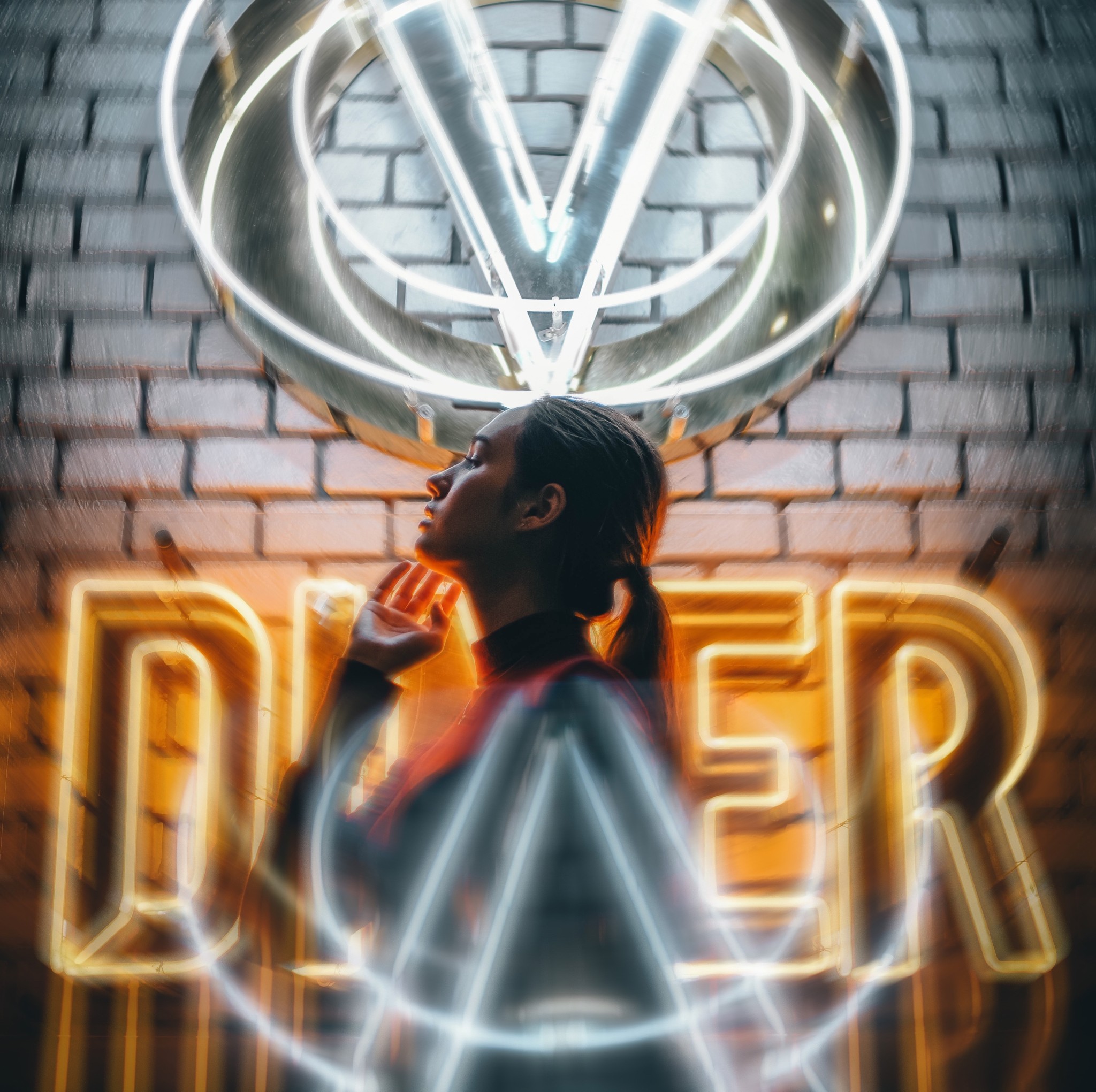 A girl with her hand near her face standing in front of yellow and white neon signs