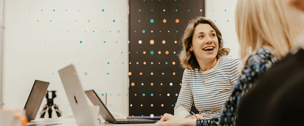 Woman sitting in meeting smiling away from laptops